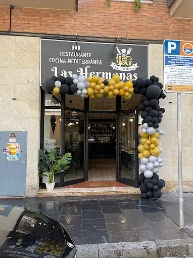 Un restaurante con globos delante y un coche aparcado delante.