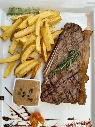 Un plato blanco cubierto con un filete y papas fritas.