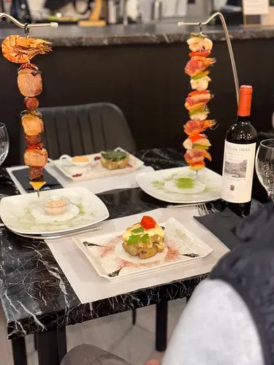 Una mesa con platos de comida y una botella de vino.