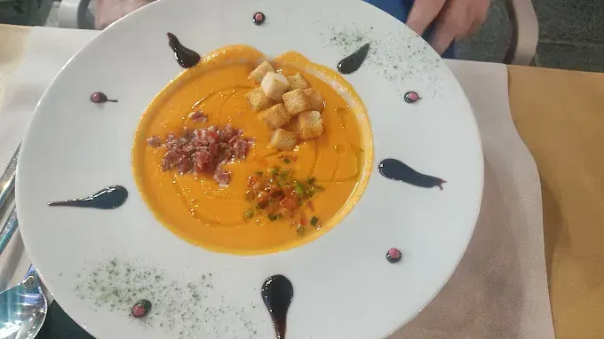 Un plato blanco cubierto con sopa y crutones sobre una mesa.