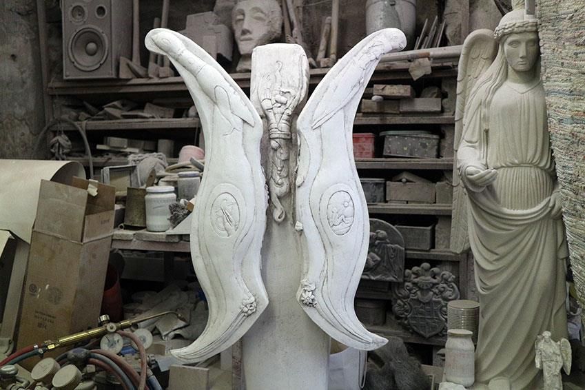 Eine Statue einer Frau mit Flügeln ist von anderen Statuen umgeben