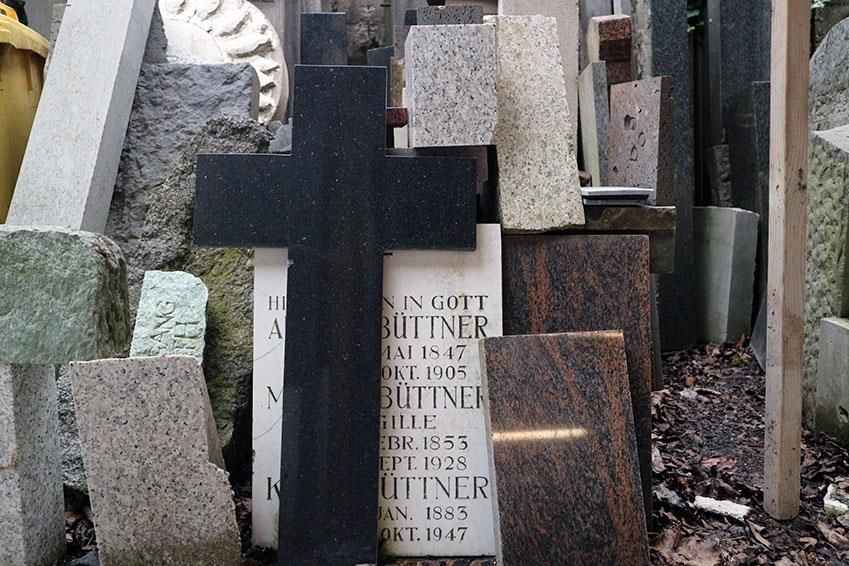 Auf einem Grab auf einem Friedhof steht ein Kreuz