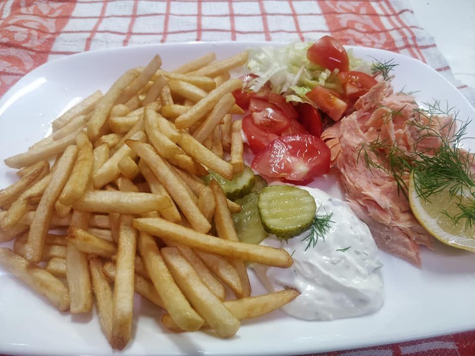 Lautanen ranskalaisia, savulohta, tomaatteja, suolakurkkuja, salaattia ja nokare valkokastiketta.