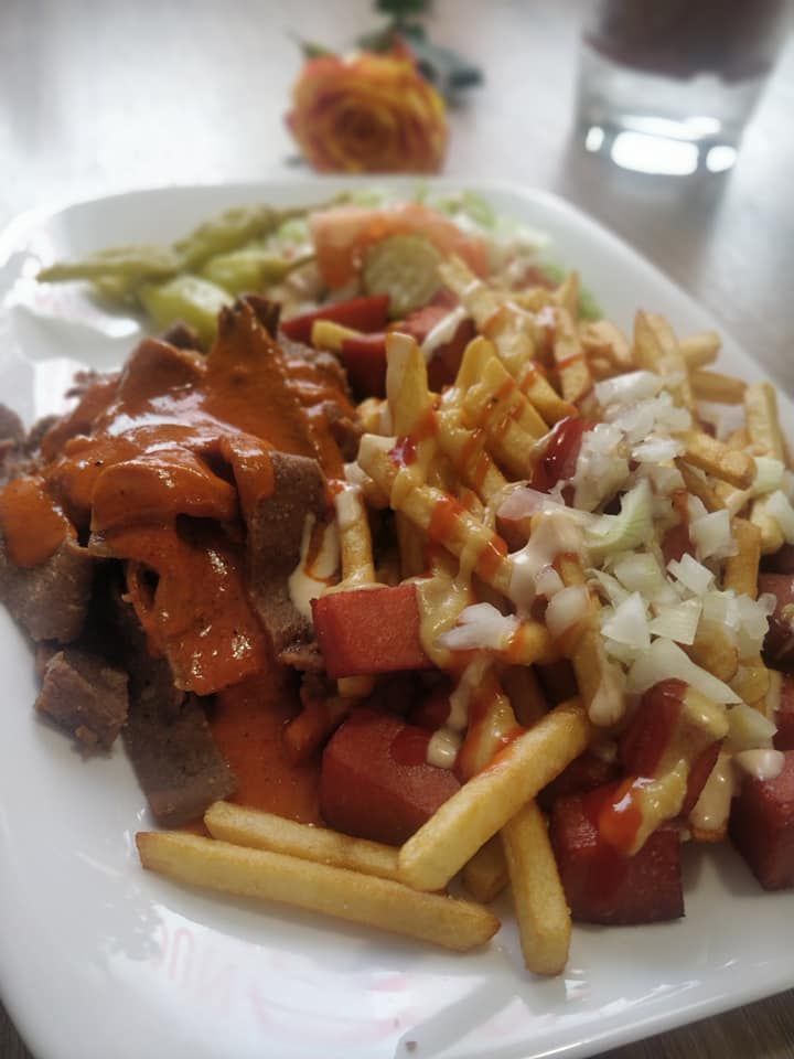 Lautanen döner kebab -lihaa, ranskalaisia, makkaraa, salaattia ja kastiketta.