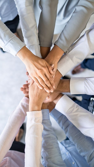 Un groupe de personnes posant leurs mains les unes sur les autres en cercle.