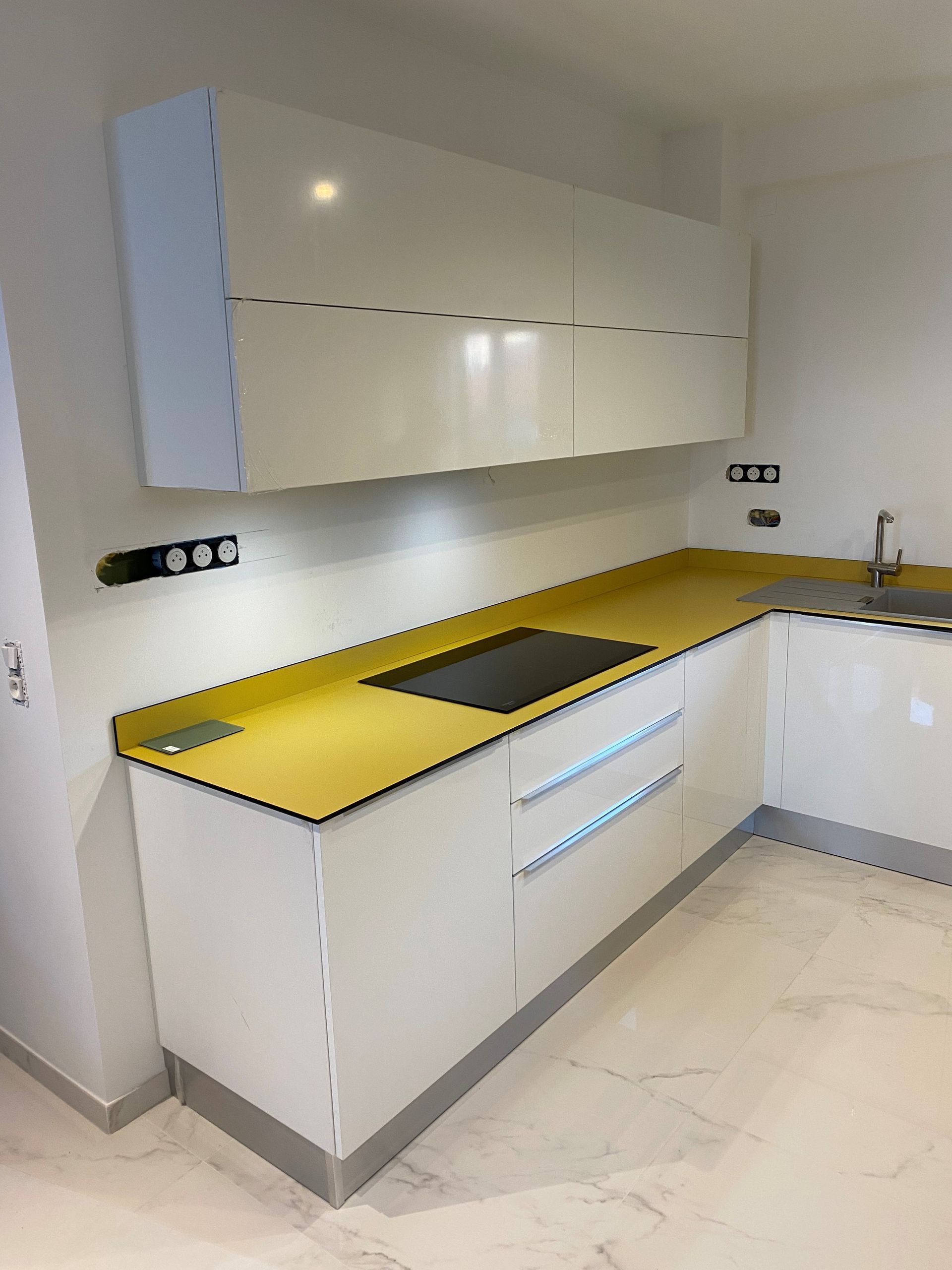 Cuisine blanche moderne avec comptoir et armoires jaunes.