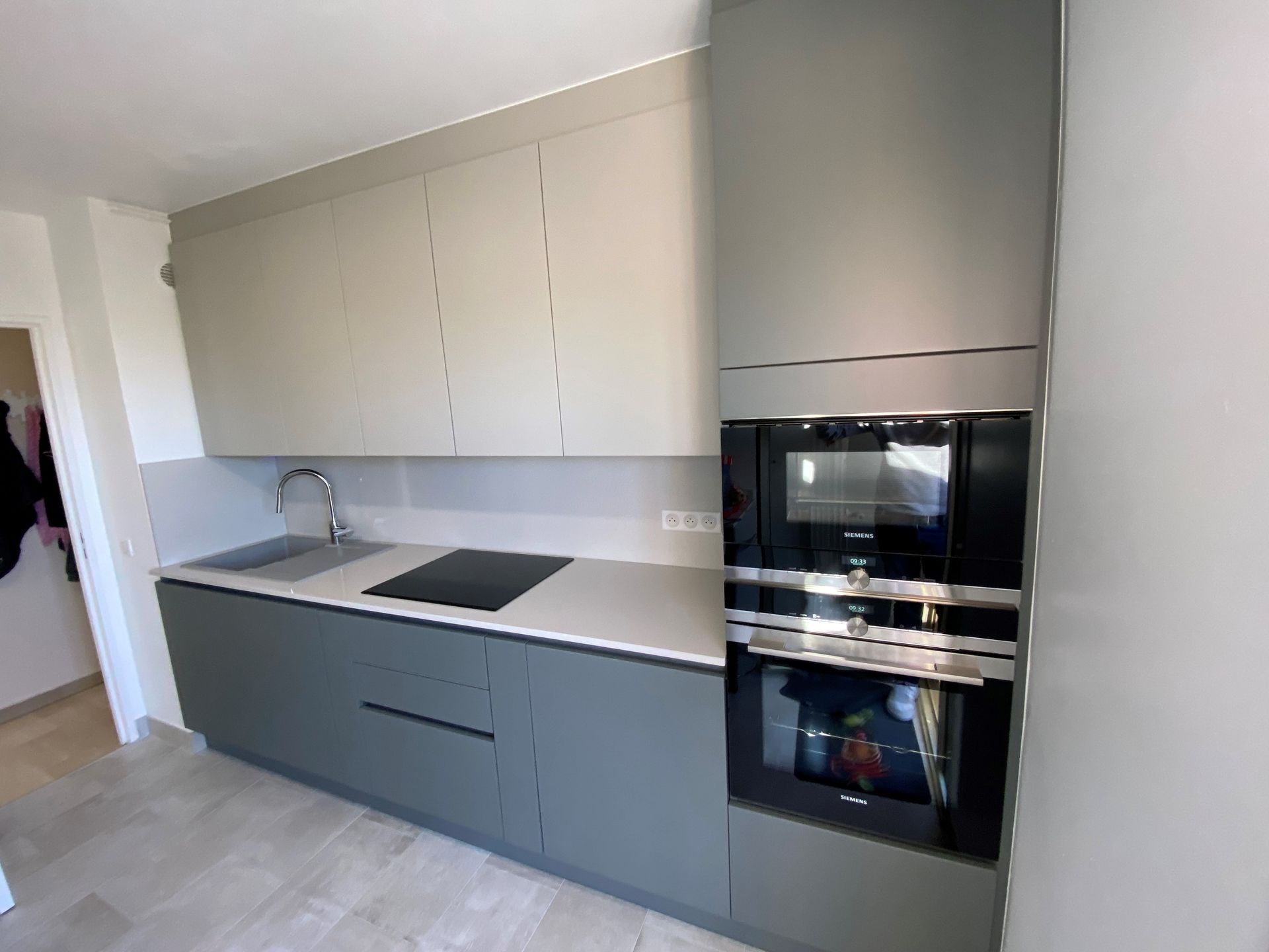 Cuisine grise moderne avec four et micro-ondes intégrés, armoires grises et comptoir clair.