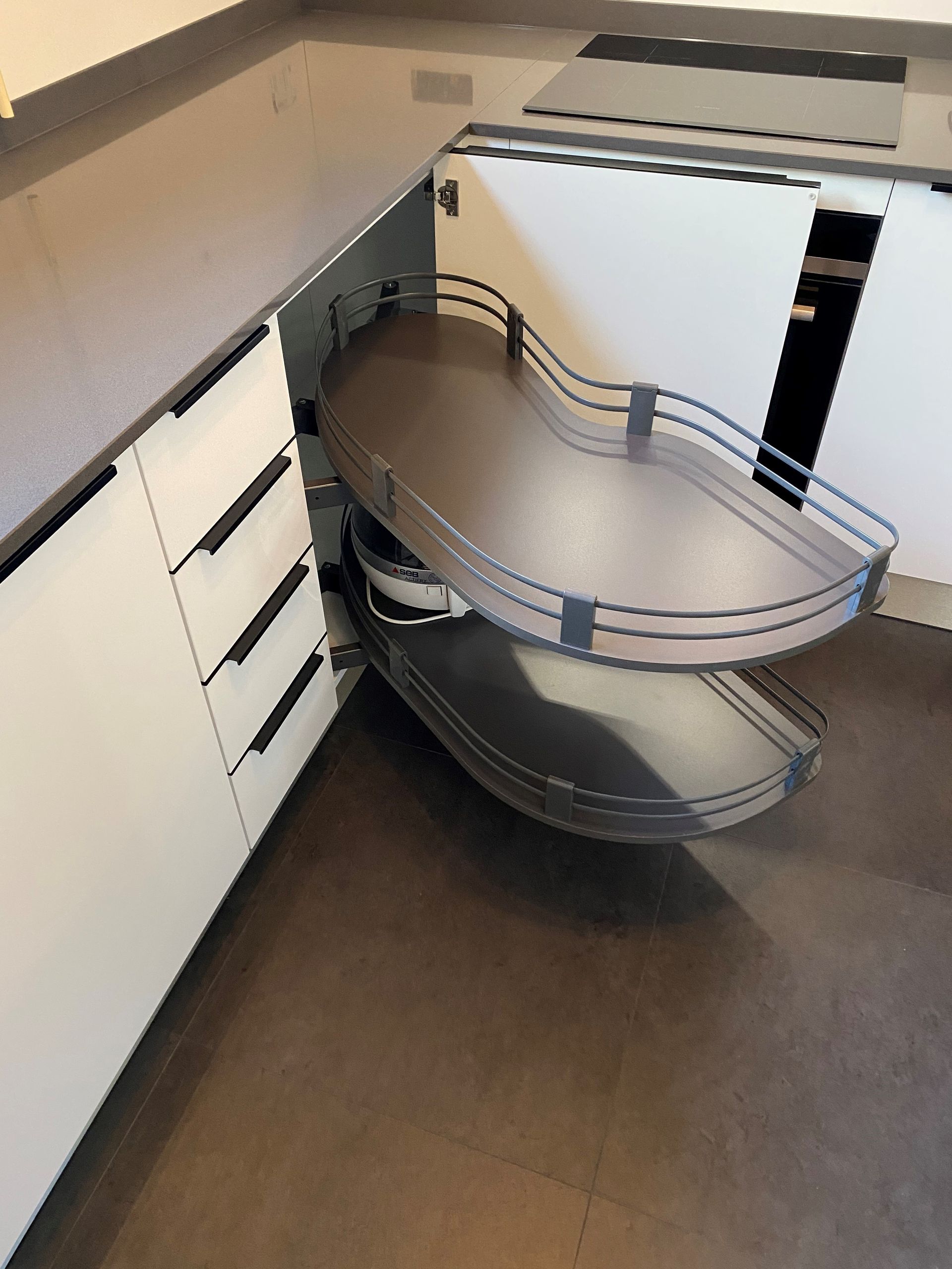 Meuble de cuisine d'angle avec tablettes coulissantes, brun et blanc avec quincaillerie en acier inoxydable.