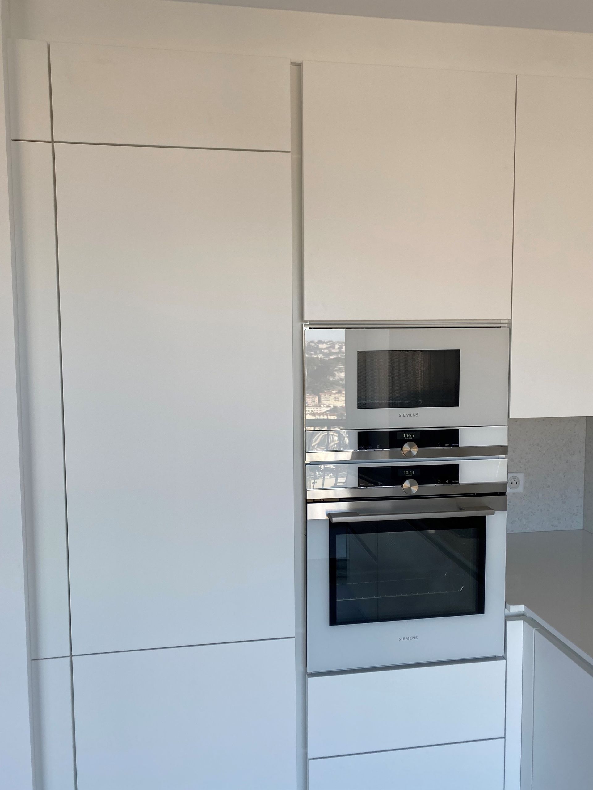 Armoires de cuisine encastrées blanches avec un ensemble micro-ondes/four en acier inoxydable.