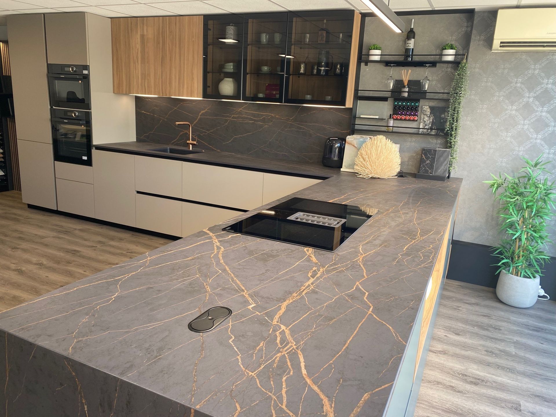 Cuisine moderne avec îlot central et placards gris. Veinures dorées, touches de bois et électroménagers intégrés.