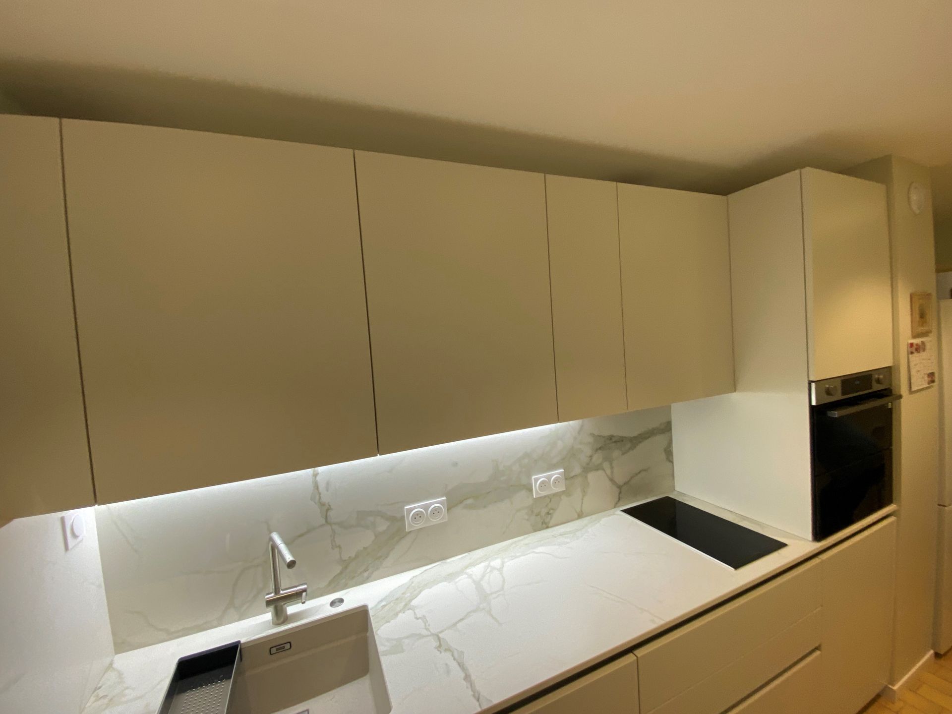 Cuisine blanche moderne avec dosseret en marbre, armoires, évier et four.