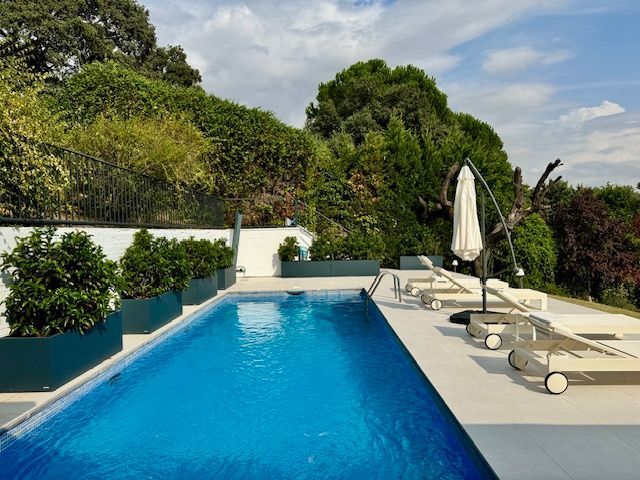 Una gran piscina con sillas y sombrillas alrededor.