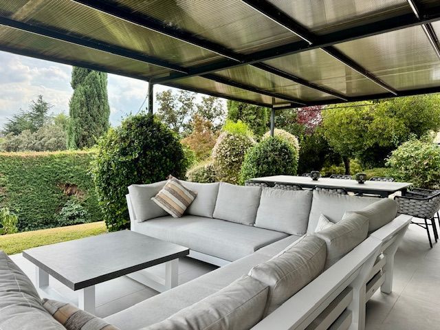 Un patio con sofá, mesa y sillas bajo un dosel.