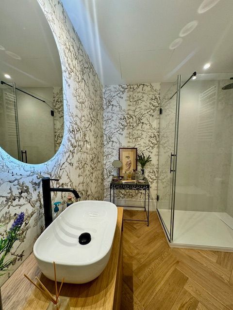 Un baño con lavabo, espejo y ducha a ras de suelo.