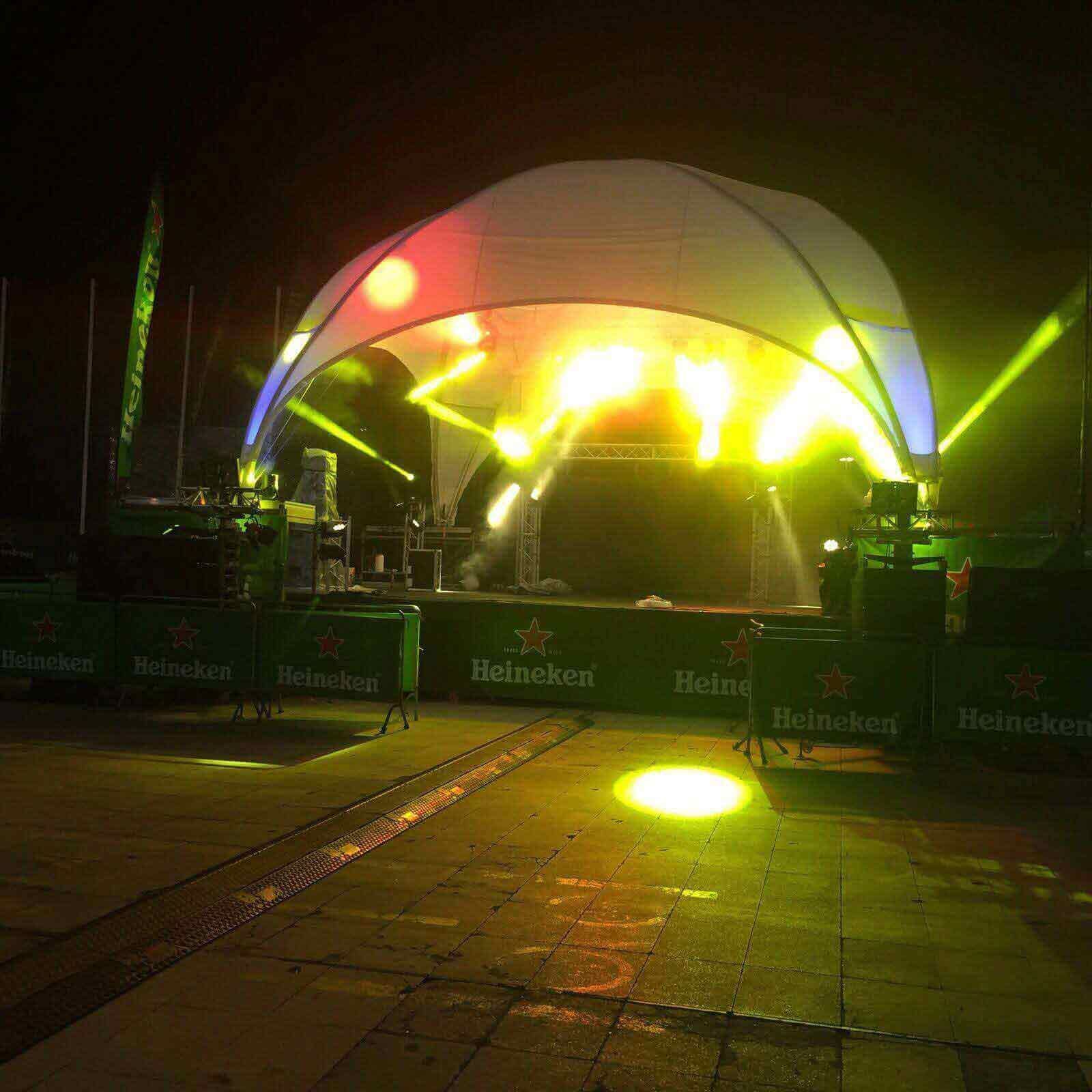 Un escenario está iluminado por la noche con un cartel de Heineken al fondo.