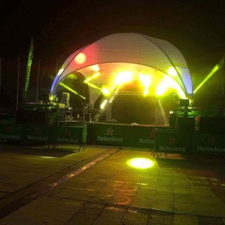 Un escenario está iluminado por la noche con un cartel de Heineken al fondo.