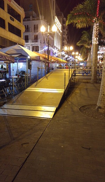 Una fila de paraguas están alineados en una acera en una ciudad por la noche.