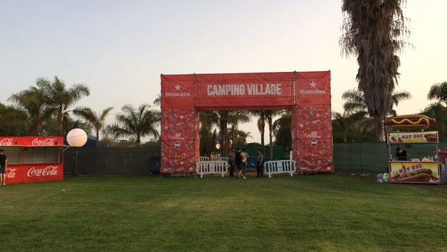 Un gran cartel rojo que dice que el camping está en medio de un campo de hierba.