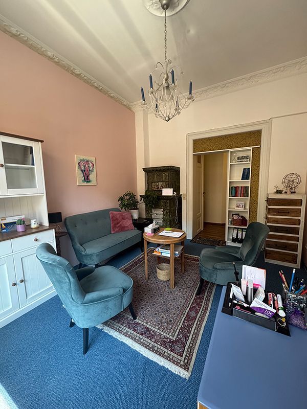 Wohnzimmer mit blauem Teppich und blauem Stuhl, gemütlich und einladend gestaltet.