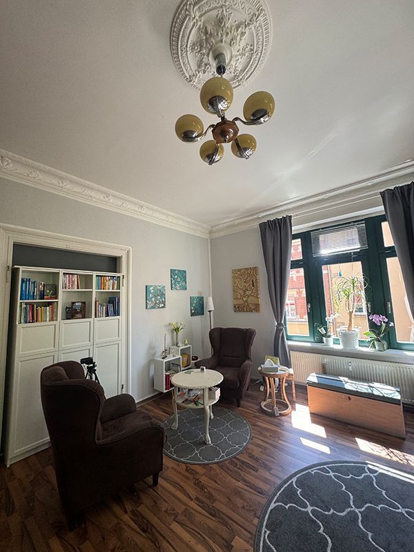 Ein Wohnzimmer mit einem Sofa, einem Stuhl und einem Bücherregal.