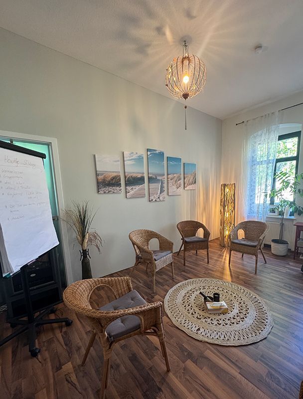 Ein Raum mit Rattanstühlen und einer weißen Tafel an der Wand.