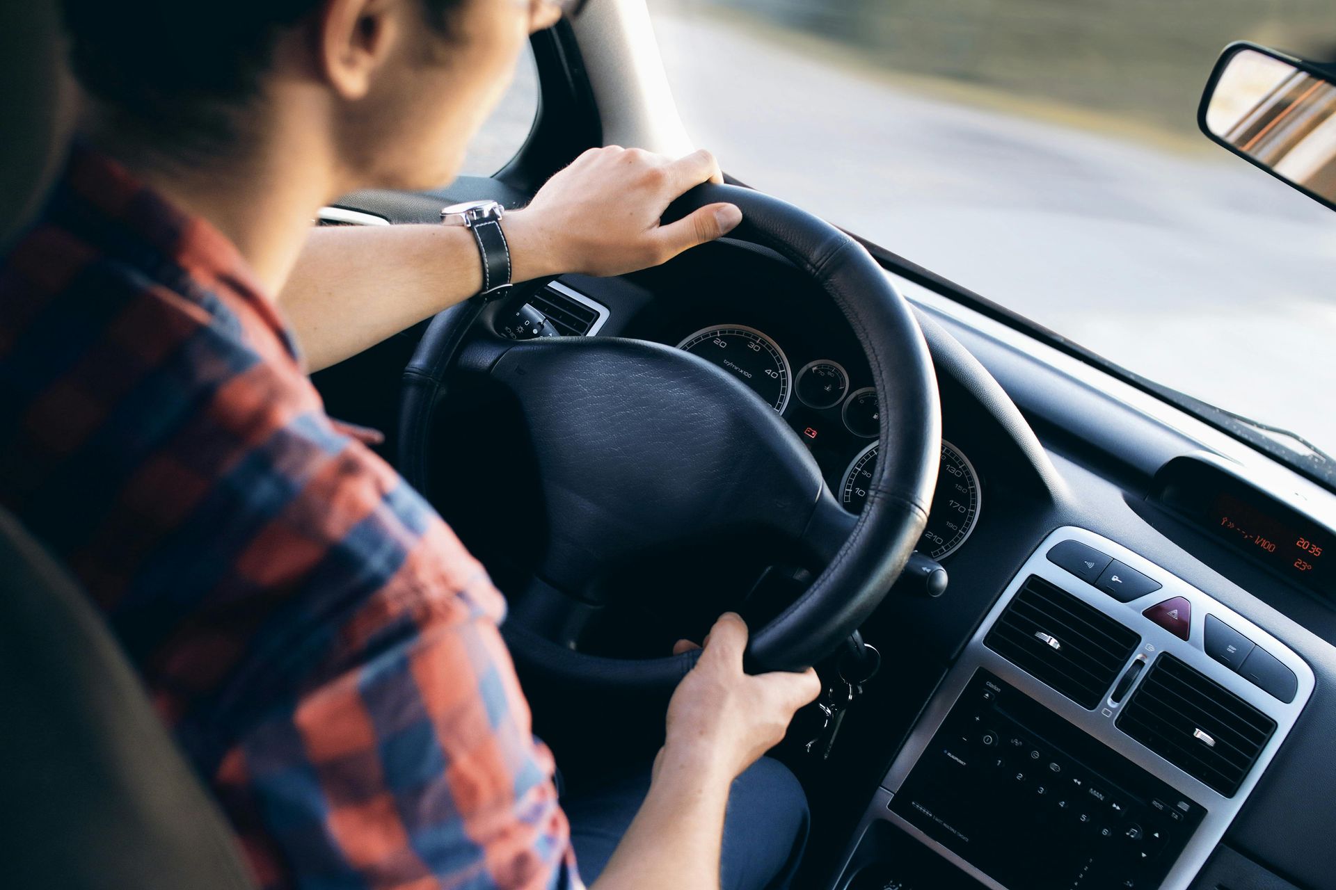 Ein Mann in einem karierten Hemd fährt Auto.