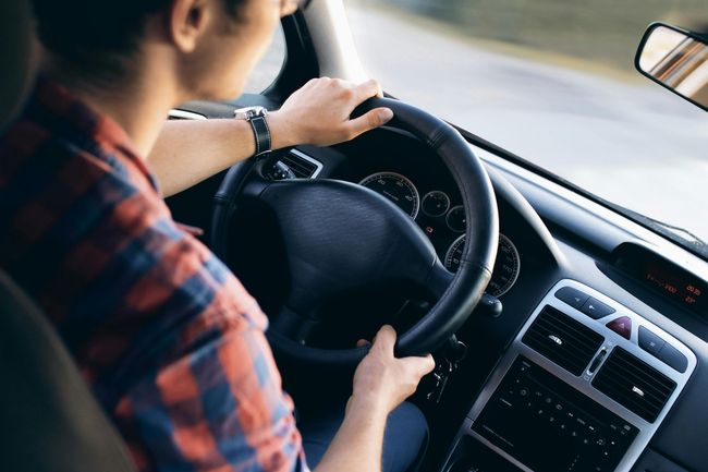 Ein Mann in einem karierten Hemd fährt Auto.