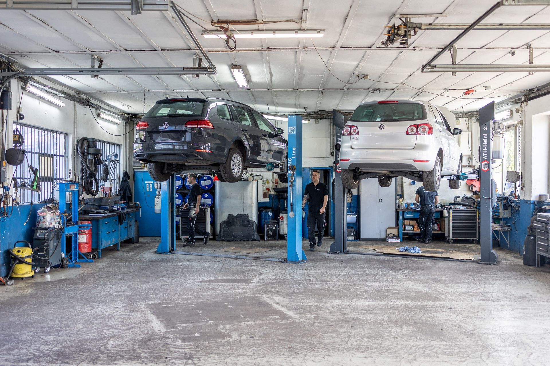 Zwei Autos stehen auf Hebebühnen in einer Garage.