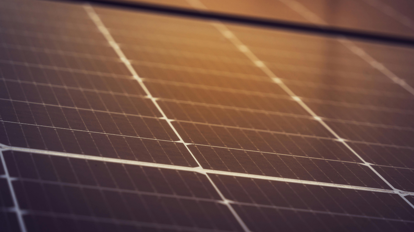 Primer plano de un conjunto de paneles solares, con líneas de cuadrícula y un degradado de color cálido y dorado.