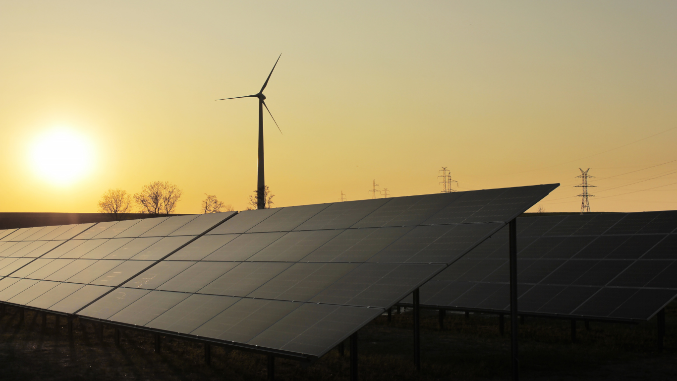 Paneles solares y turbinas eólicas al atardecer, produciendo energía limpia.