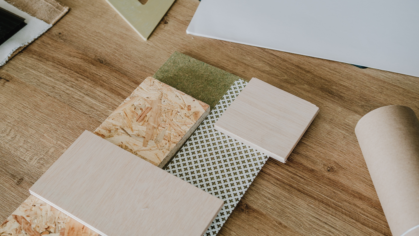 Azulejos, muestras de piedra y un tubo descansan sobre una superficie de madera, mostrando muestras de materiales.