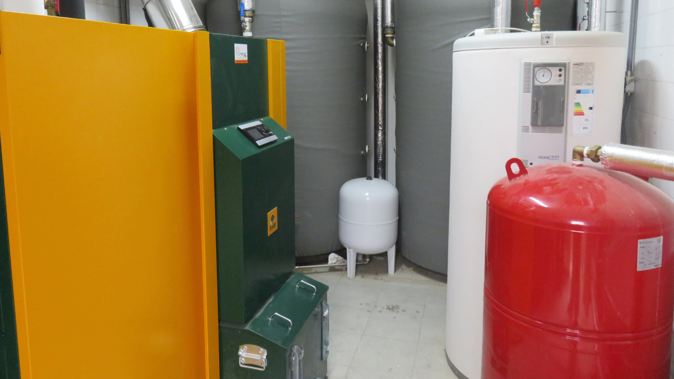 Sistema de calefacción de color amarillo y verde con varios tanques en un cuarto de servicio.