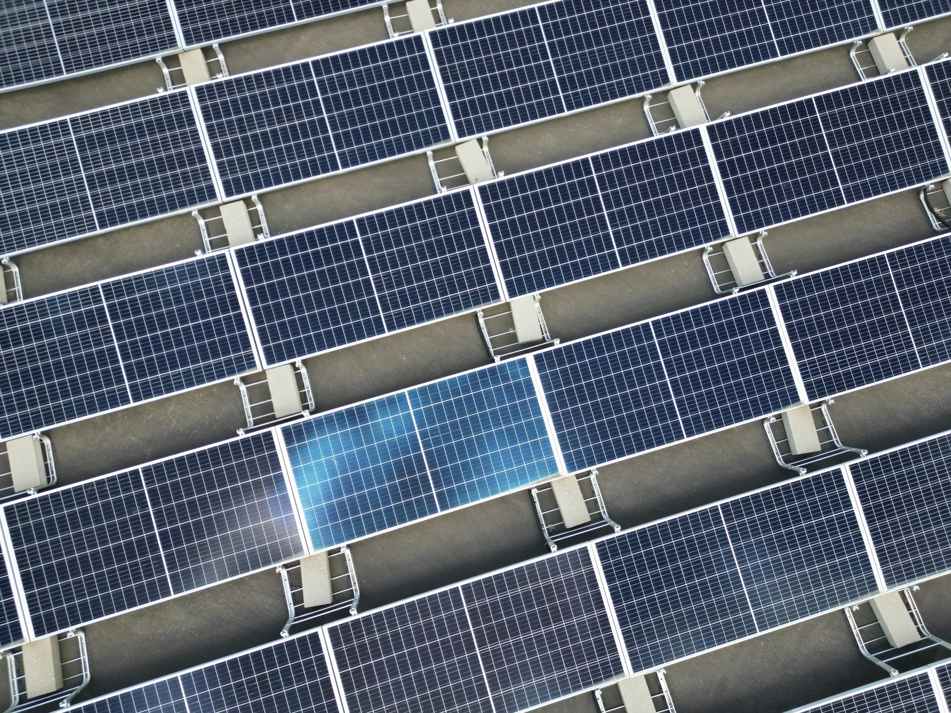 Paneles solares, rejilla en ángulo. Un panel está iluminado, los demás son de color azul oscuro.