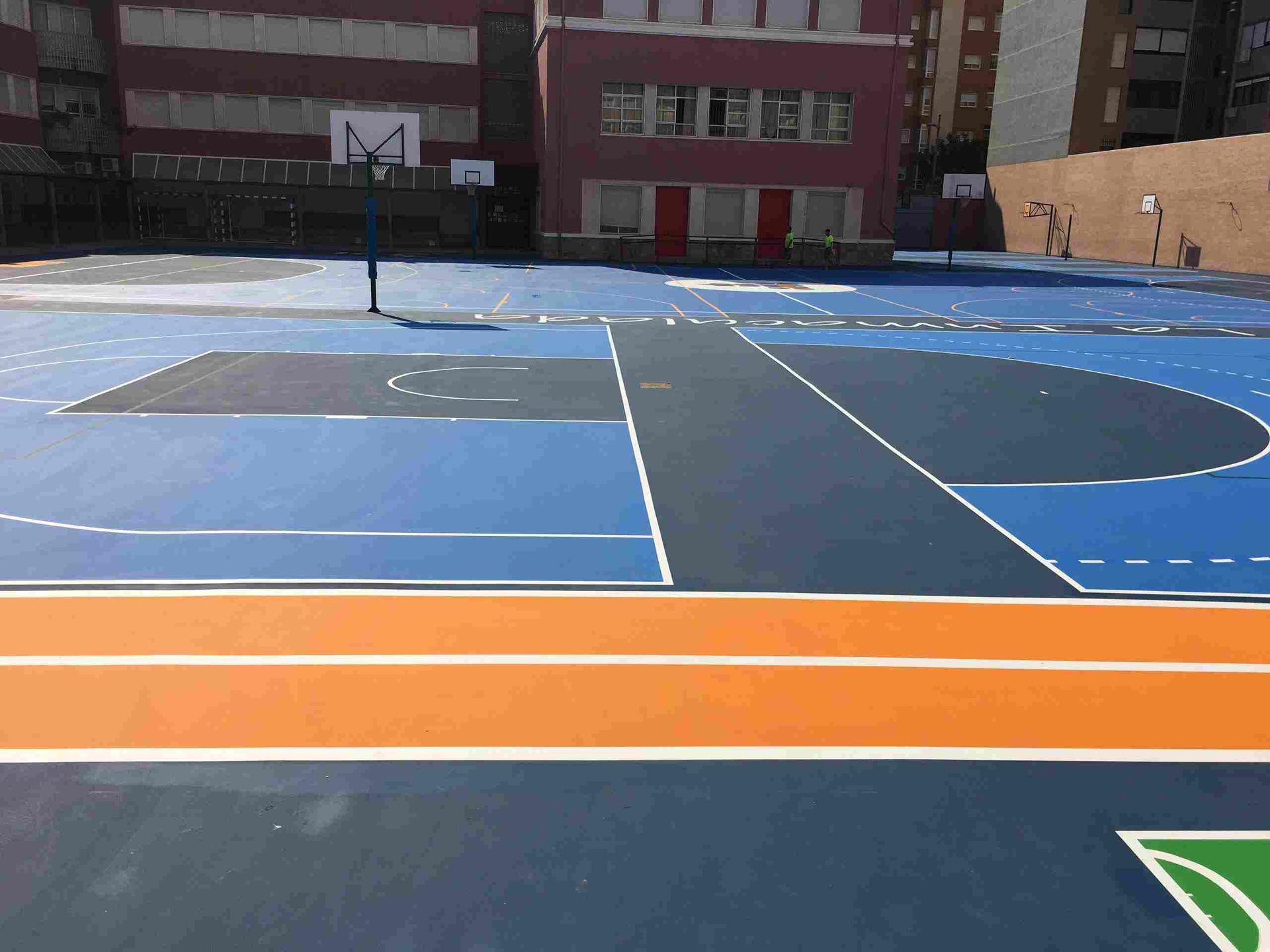 Una cancha de baloncesto azul y naranja frente a un edificio.