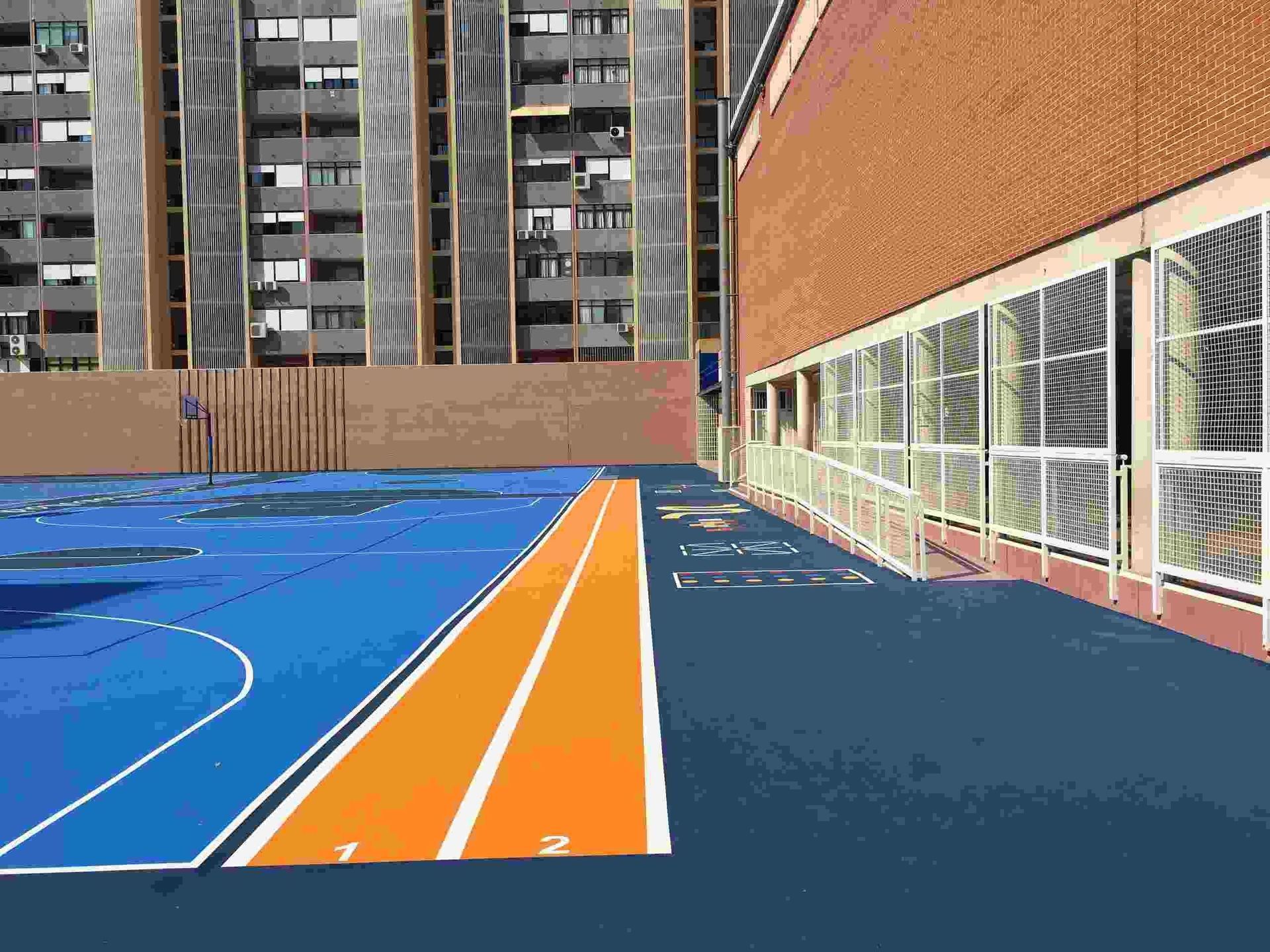 Una cancha de baloncesto azul y naranja frente a un edificio.