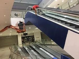 Un hombre está limpiando una escalera mecánica en un centro comercial.