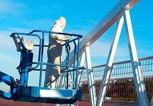 Un hombre está de pie dentro de un cubo encima de una grúa.