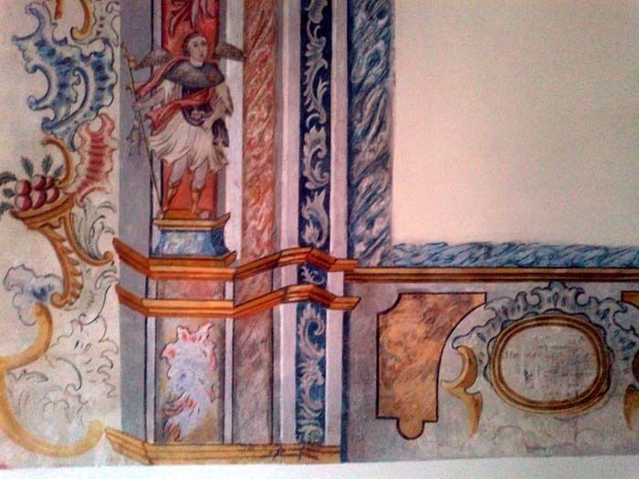 Una pintura de una pared con una estatua de un ángel en ella.