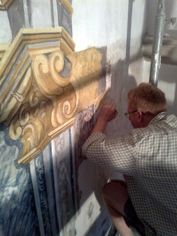 Un hombre está trabajando en una pintura en una pared.