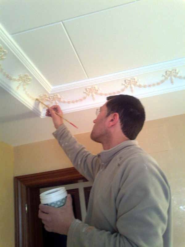 Un hombre está pintando un techo con un pincel.
