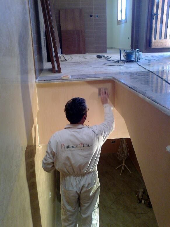 Un hombre con un mono blanco está pintando una pared.