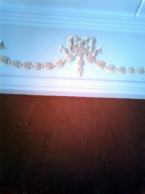 Una moldura blanca con un lazo sobre una pared marrón.