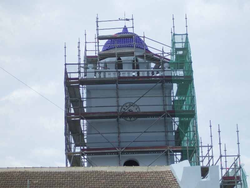 Una torre de reloj con andamios a su alrededor y una cúpula azul en la parte superior
