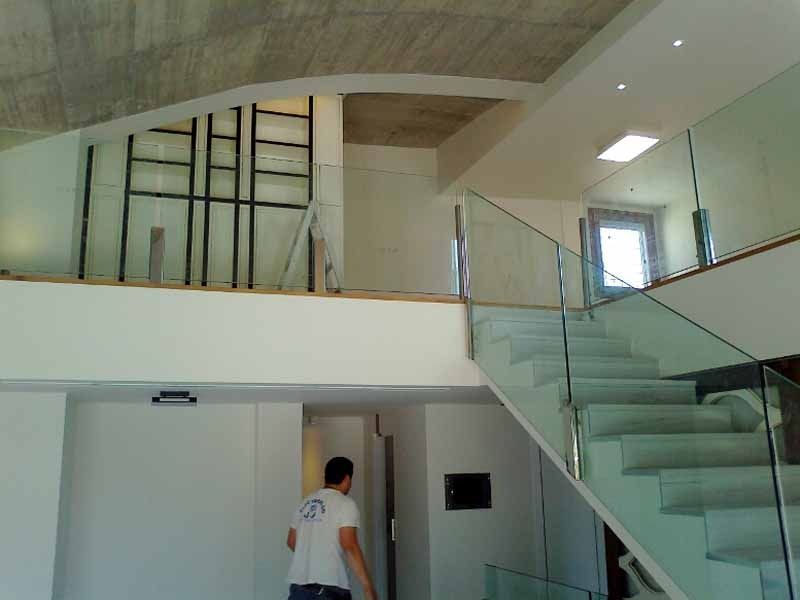 Un hombre baja unas escaleras con barandilla de cristal.