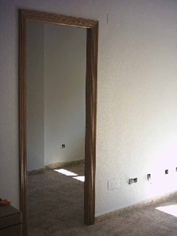 Una puerta en una habitación con paredes blancas y un marco de madera.