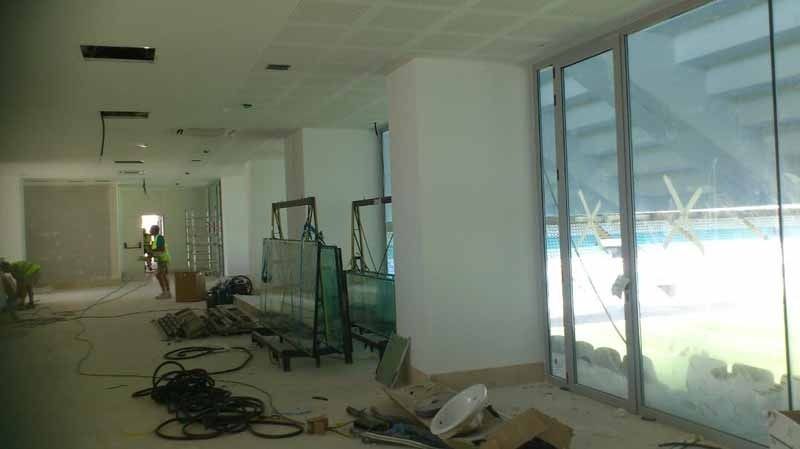 Una habitación grande con muchas ventanas y una piscina al fondo.