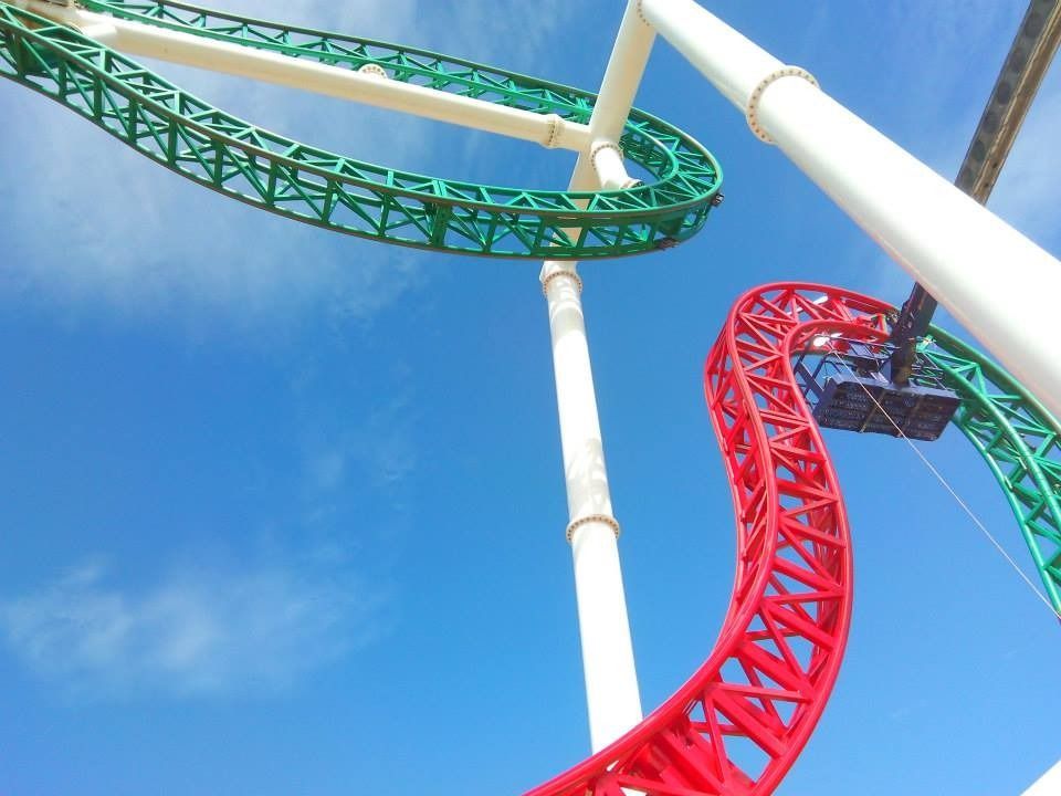 Una montaña rusa roja y verde contra un cielo azul