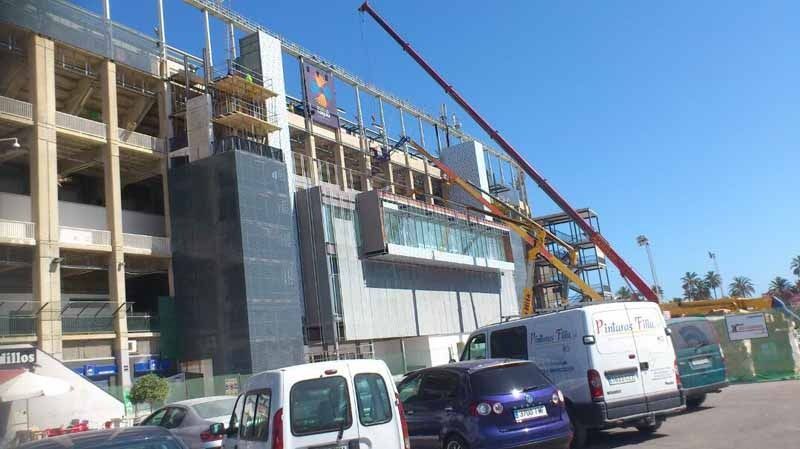Un edificio en construcción con muchos coches aparcados delante.