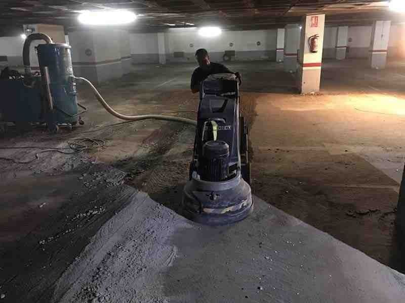 Un hombre está usando una máquina para moler hormigón en un estacionamiento.