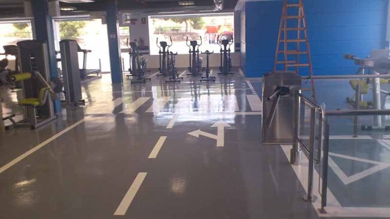 Un gimnasio con muchos equipos de ejercicio y un lugar de estacionamiento para discapacitados.